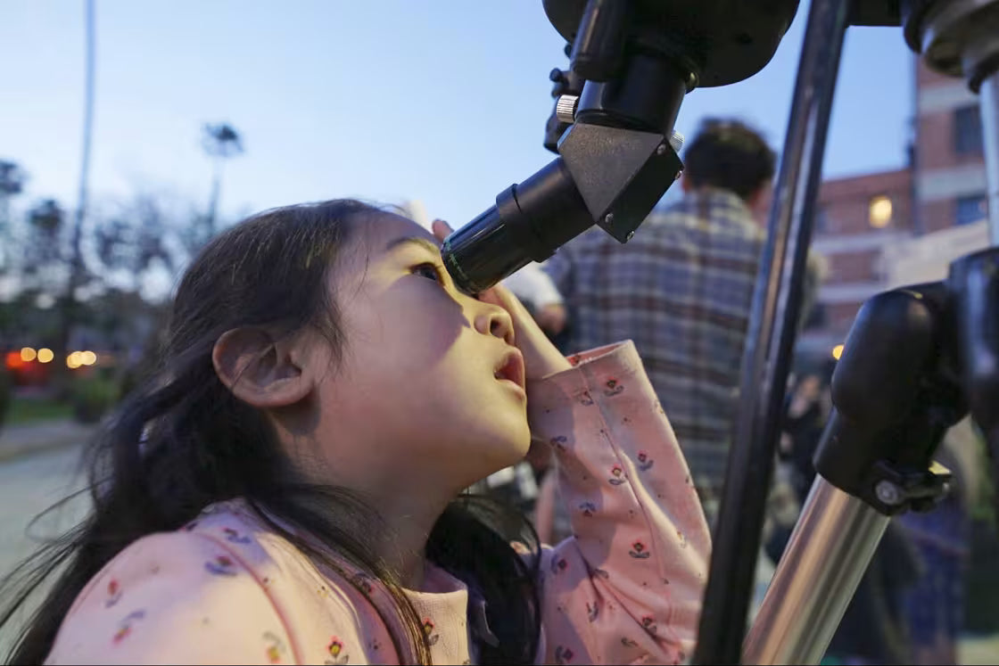 A child looks through a telescope during an outdoor astronomy club event in Los Angeles, on April 18, 2025.